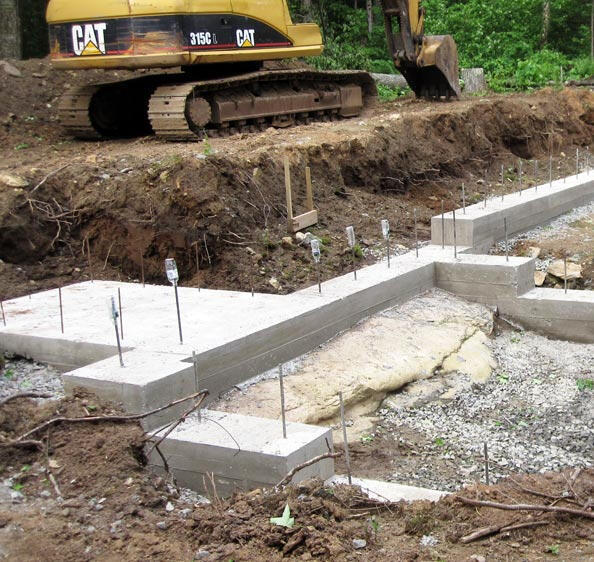 Excavator next to fresh foundation.